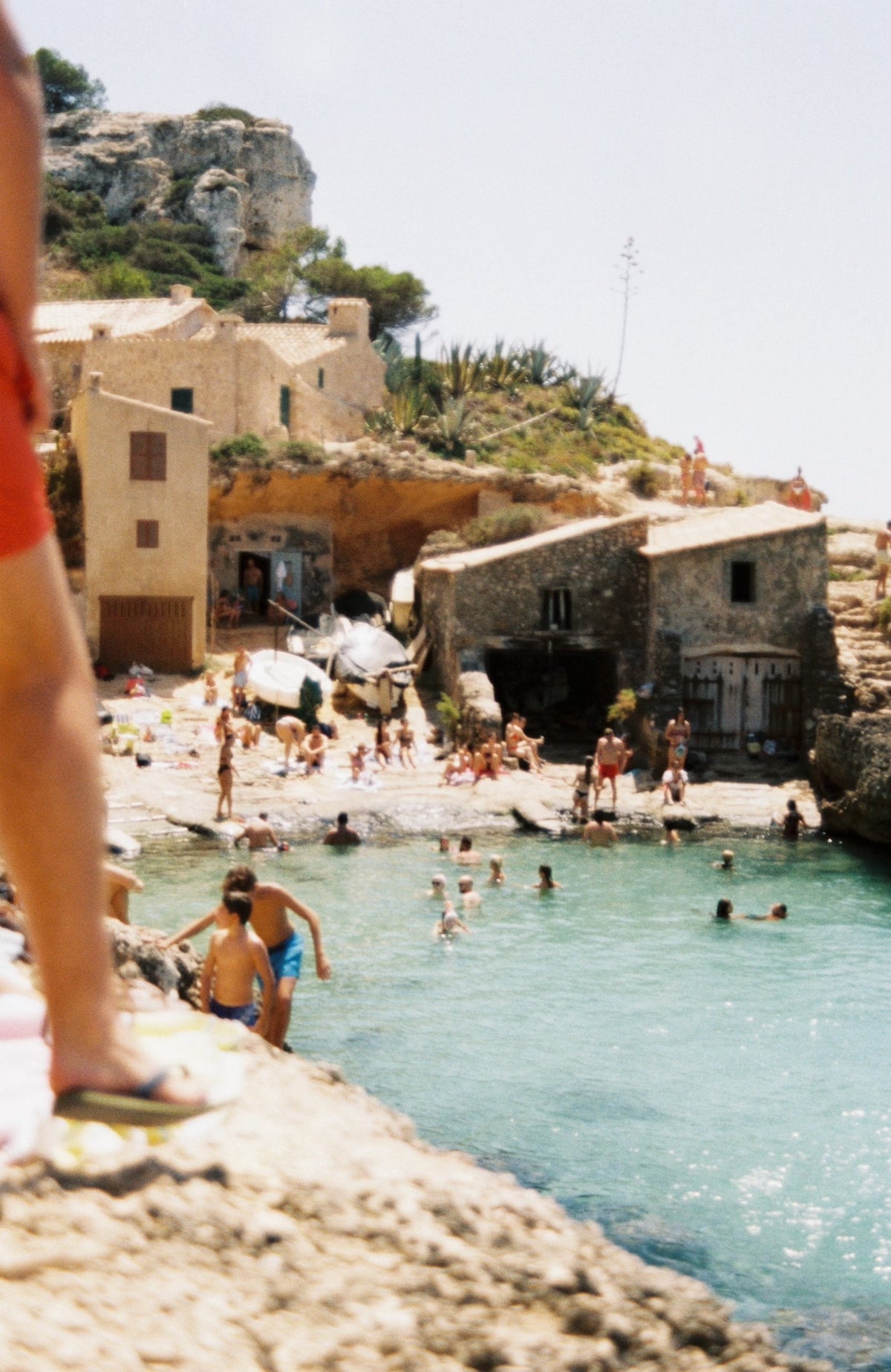 Worn, sunny beach with swimmers and sun bathers